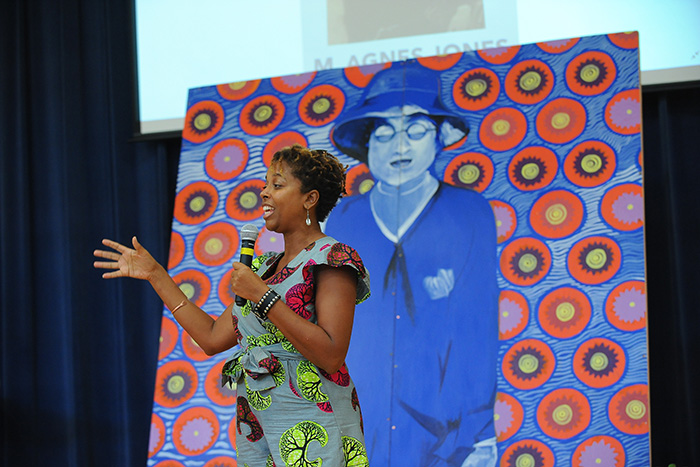 Artist Charmaine Minniefield speaks to the crowd, holding a microphone